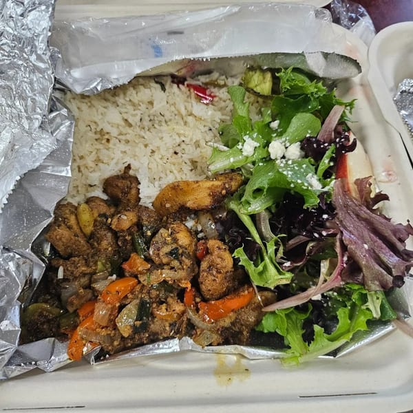 A Greek chicken and rice dish with a side salad, served in a takeout container.