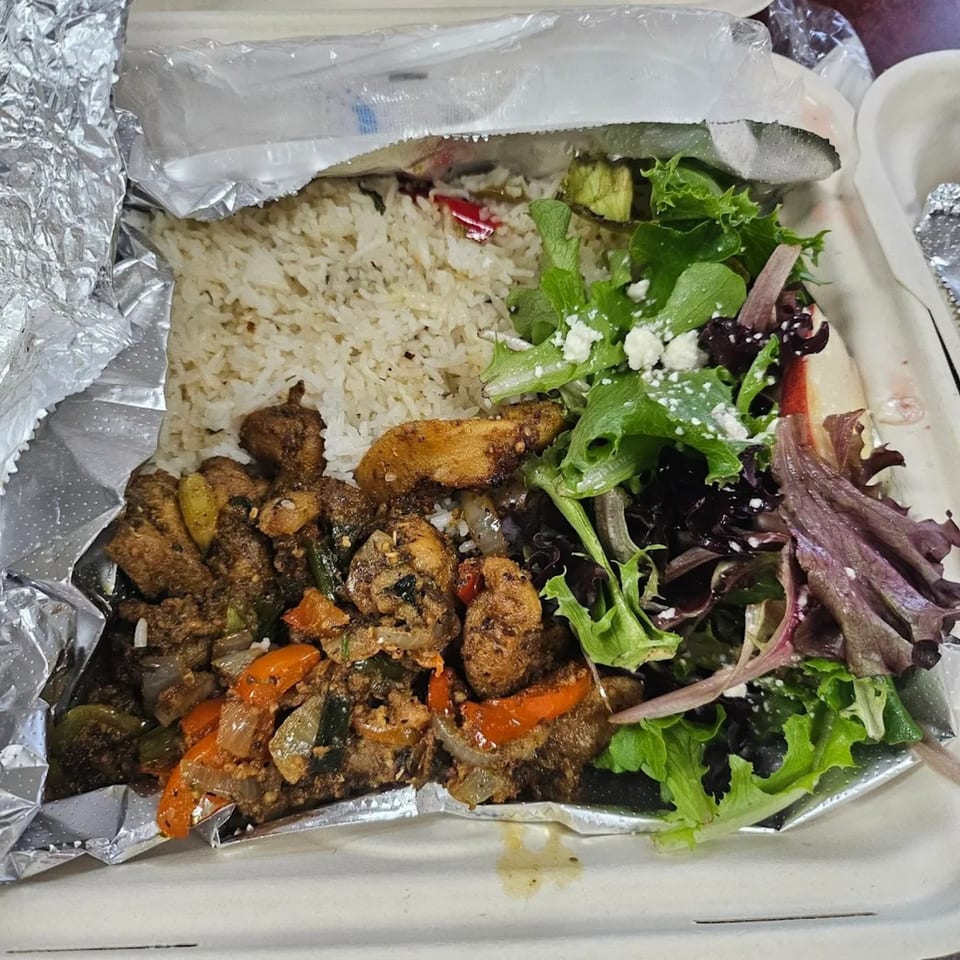 A Greek chicken and rice dish with a side salad, served in a takeout container.